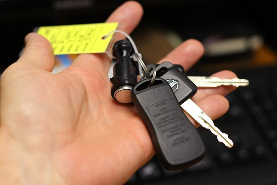 Vendeur qui tient les clés d'une voiture d'occasion à vendre dans sa main